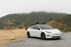 white tesla model 3 parked beside mountain during daytime